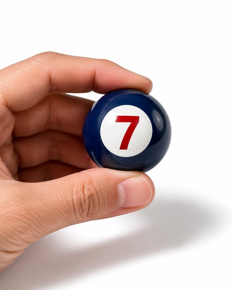 A hand holding a navy lottery ball with the number 7